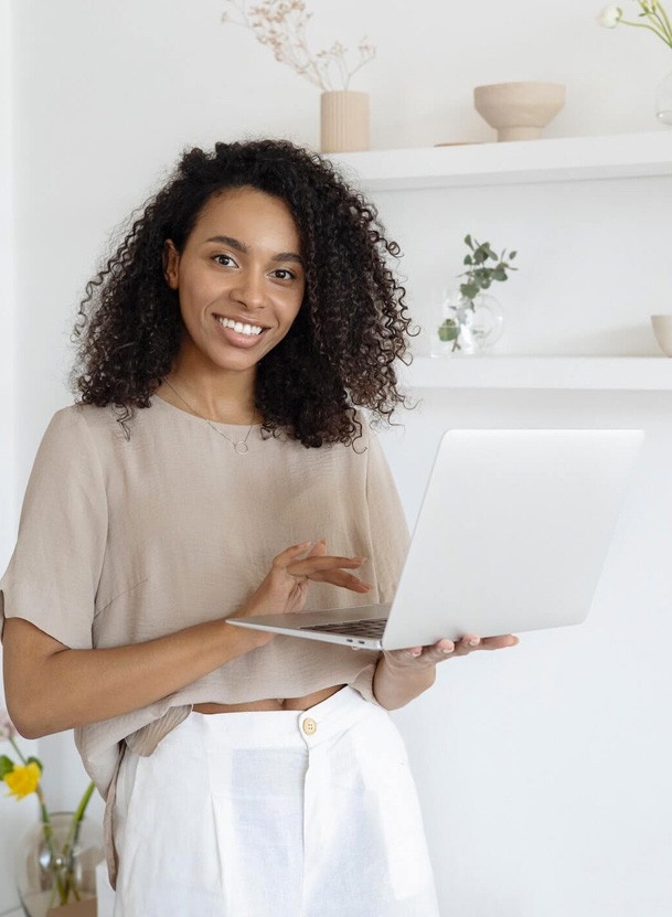 Woman sitting on window sill with laptop in her lap